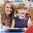 Teacher Helping Elementary Scool Pupil To Use Digital Tablet